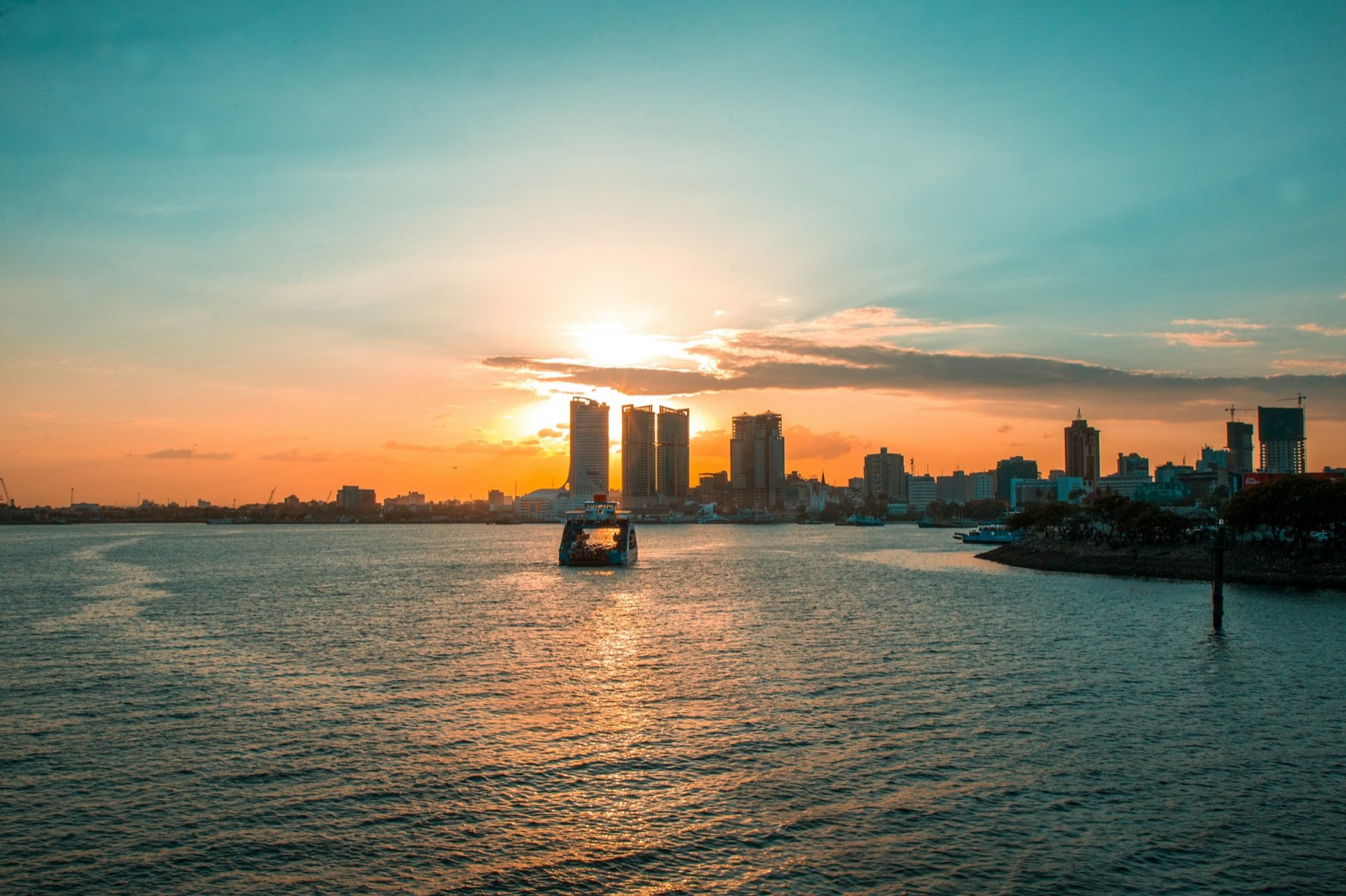 A boat on the water at sunset, with the Dar es Salaam skyline behind it